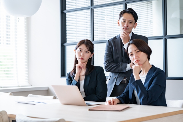 悩んでいる3人のスーツの男女