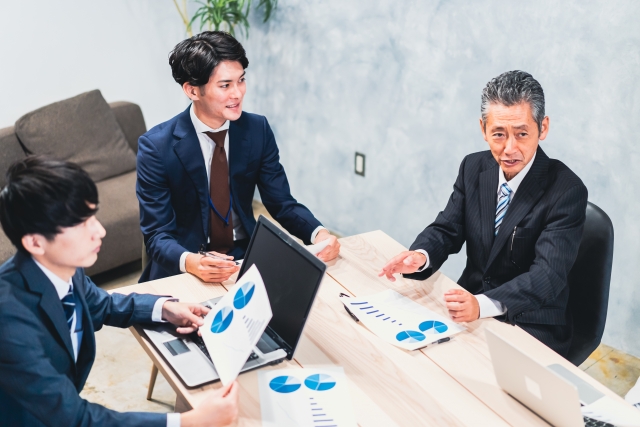 グラフデータを見て話し合う複数人のビジネスパーソン