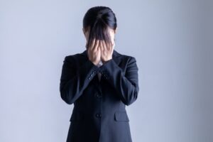 顔を覆うスーツを着た女性