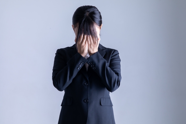 顔を覆うスーツを着た女性