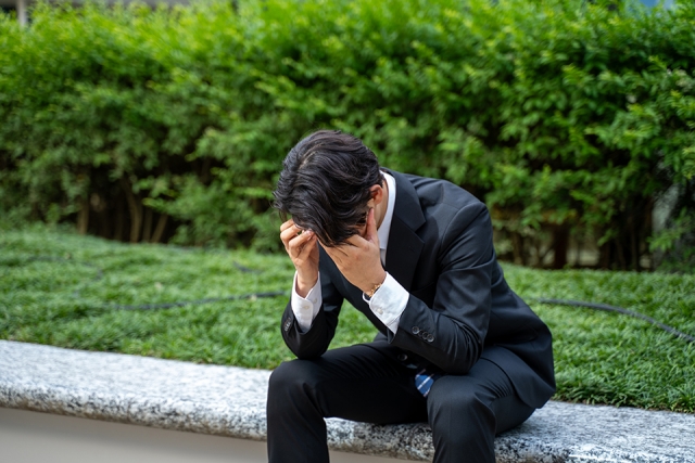 頭を抱えるスーツの男性