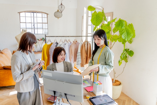 洋服のデザインを話し合う3人の女性