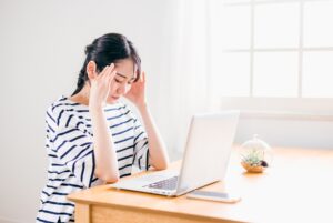 パソコンを見て頭を抱える女性